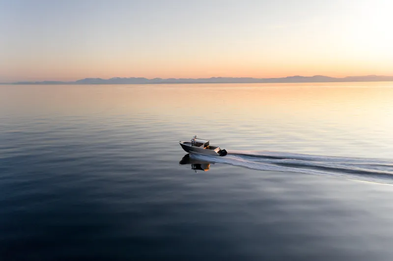 Slide: The Image of 2025 Jasper Marine Defender 22 boat cruising on calm water at sunset - 10
