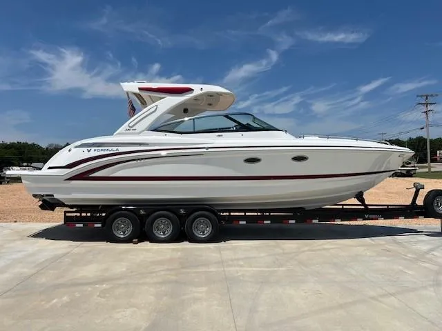 The Image of 2025 Formula 330 Crossover Bowrider I/O on a trailer under a clear blue sky. - 1