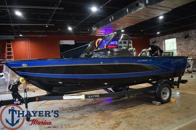 Slide: The Image of 2024 Lund 1875 Impact XS Sport boat on trailer at Thayer's Marine showroom. - 29