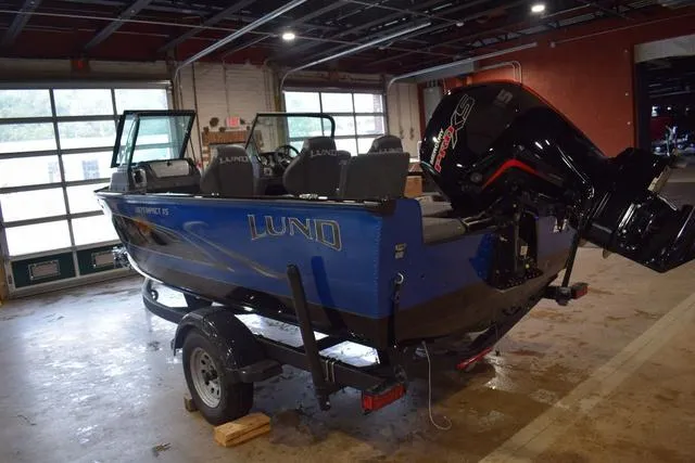 Slide: The Image of 2024 Lund 1875 Impact XS Sport boat in a garage, blue exterior, on a trailer. - 30
