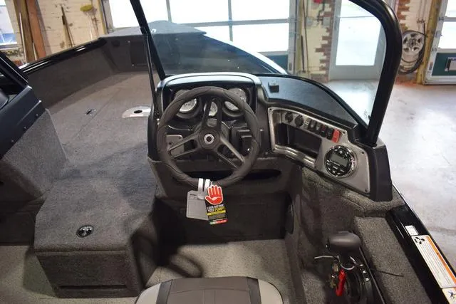 Slide: The Image of 2024 Lund 1875 Impact XS Sport boat interior, featuring steering wheel and control panel. - 32