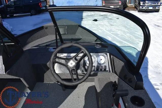 Slide: The Image of 2024 Lund 1650 Angler Sport boat dashboard and steering wheel in snowy outdoor setting. - 9