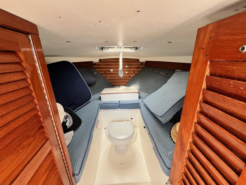 Slide: The Image of 1977 Bertram 26 Moppie cabin interior with blue cushions and wooden accents. - 18