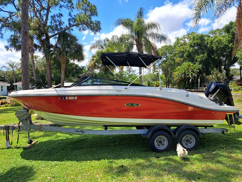 Slide: The Image of 2019 Sea Ray SPX 230 OB boat on a trailer in a lush, tropical setting. - 6
