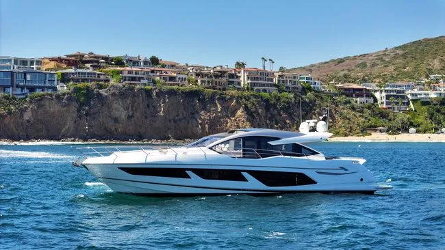 Slide: The Image of 2018 Sunseeker Predator 74 yacht cruising near coastal cliffs and luxury homes. - 0