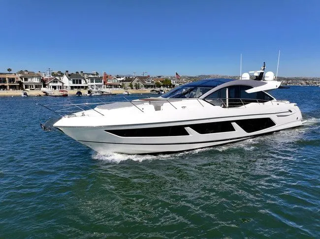 Slide: The Image of 2018 Sunseeker Predator 74 yacht cruising near coastal homes. - 2