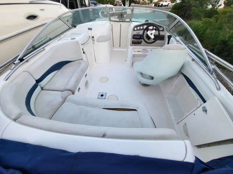 Slide: The Image of 2002 Chaparral Sunesta 233 boat interior with white seating and steering console. - 1
