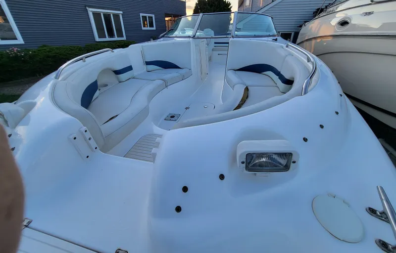 Slide: The Image of 2002 Chaparral Sunesta 233 boat with white and blue seating, docked near houses. - 2