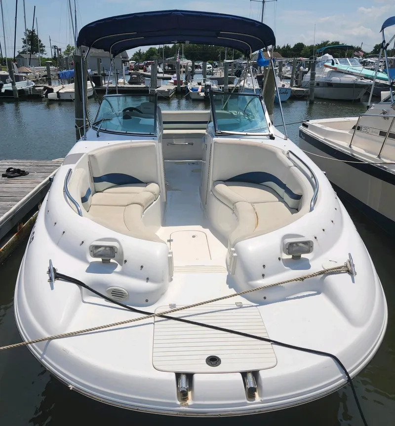 Slide: The Image of 2002 Chaparral Sunesta 233 boat docked at a marina, featuring spacious seating and sleek design. - 24
