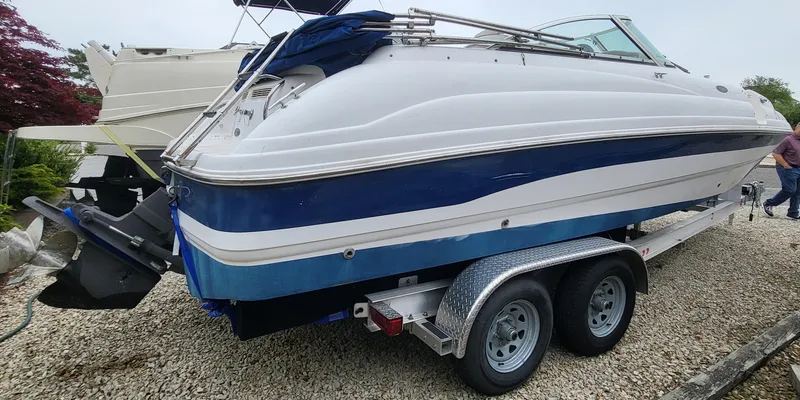 Slide: The Image of 2002 Chaparral Sunesta 233 boat on trailer, white and blue, parked on gravel. - 5