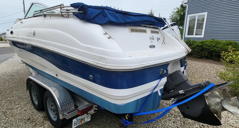 Slide: The Image of 2002 Chaparral Sunesta 233 boat on trailer, blue and white, parked on gravel driveway. - 6