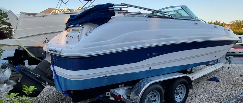 Slide: The Image of 2002 Chaparral Sunesta 233 boat on trailer, white and blue design, parked outdoors. - 9