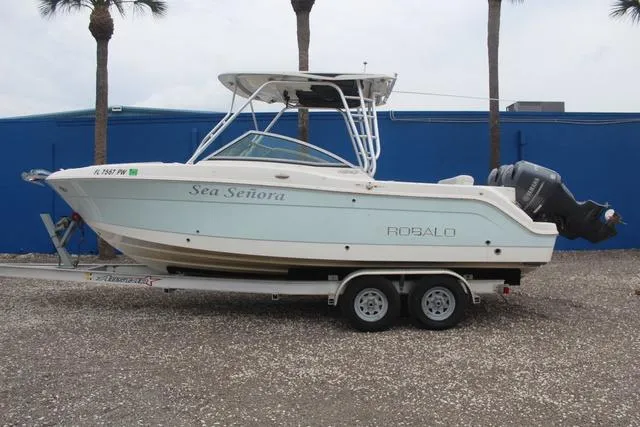 Slide: The Image of 2015 Robalo R247 boat on trailer, named Sea Señora, parked near blue wall. - 7
