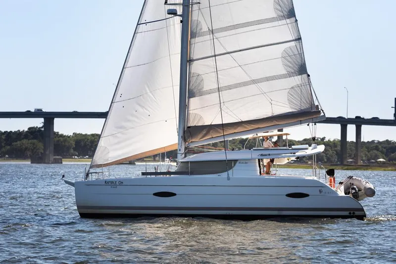 Slide: The Image of 2013 Fountaine Pajot Lipari 41 sailing catamaran on water near a bridge. - 2
