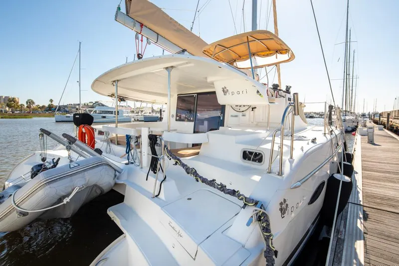 Slide: The Image of 2013 Fountaine Pajot Lipari 41 catamaran docked at marina, featuring spacious deck and dinghy. - 20