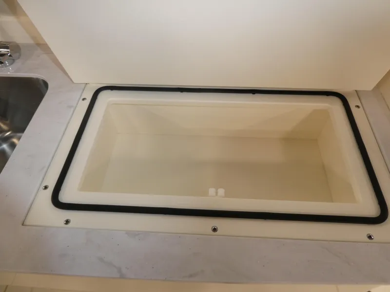 Slide: The Image of 2024 Scout 305 LXF boat storage compartment with white interior. - 38