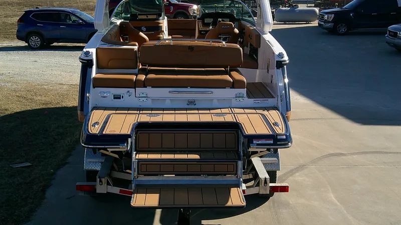 Slide: The Image of 2024 Chaparral 28 Surf boat with tan seating and swim platform, parked outdoors. - 3