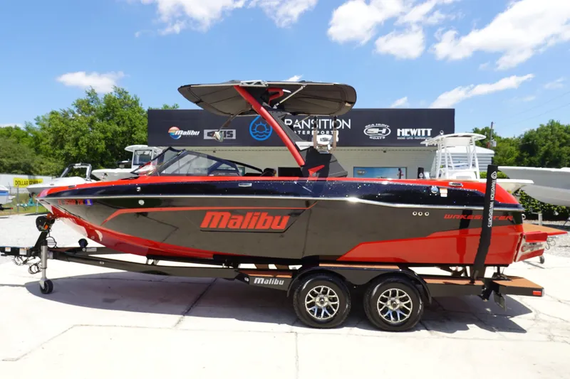 The Image of 2023 Malibu 23 LSV boat in black and red on a trailer. - 0