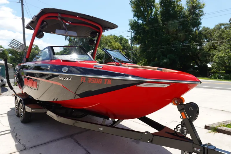 Slide: The Image of 2023 Malibu 23 LSV boat in red and black on a trailer. - 2