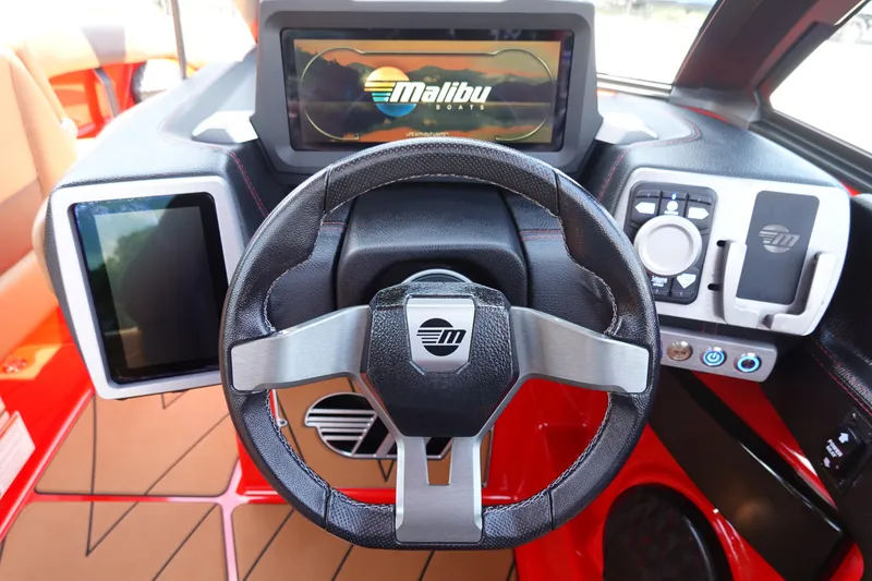 Slide: The Image of 2023 Malibu 23 LSV boat dashboard with steering wheel and digital displays. - 22