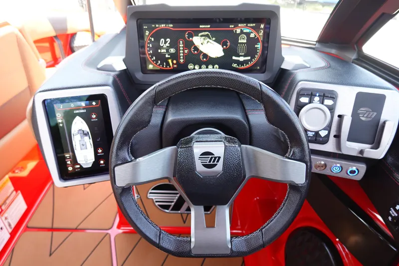 Slide: The Image of 2023 Malibu 23 LSV boat dashboard with digital displays and steering wheel. - 23