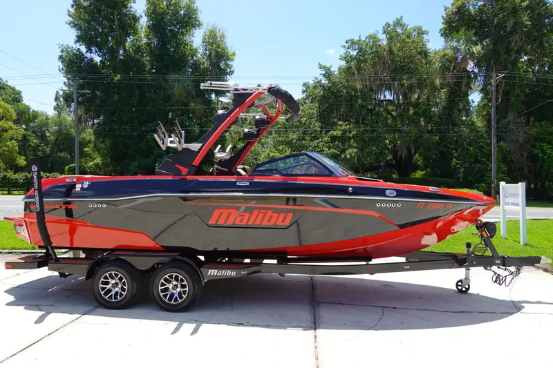 Slide: The Image of 2023 Malibu 23 LSV boat on a trailer, red and black design. - 5
