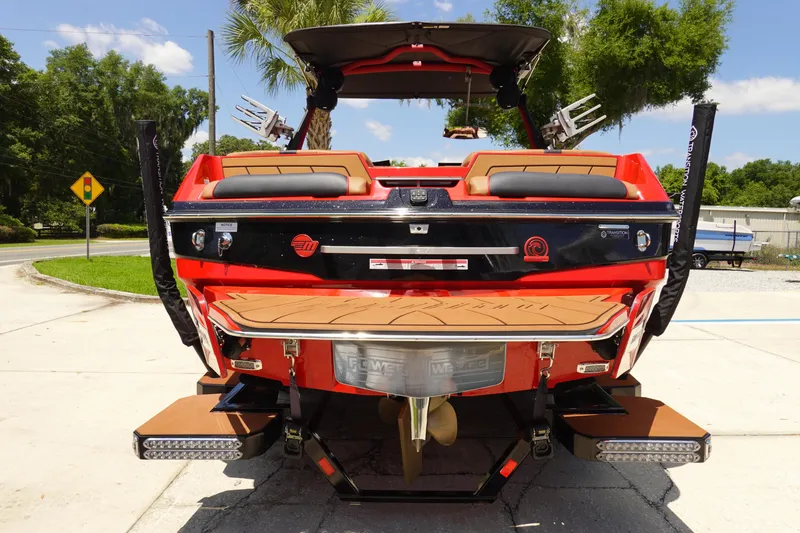 Slide: The Image of 2023 Malibu 23 LSV boat rear view with swim platform and wakeboard racks. - 7