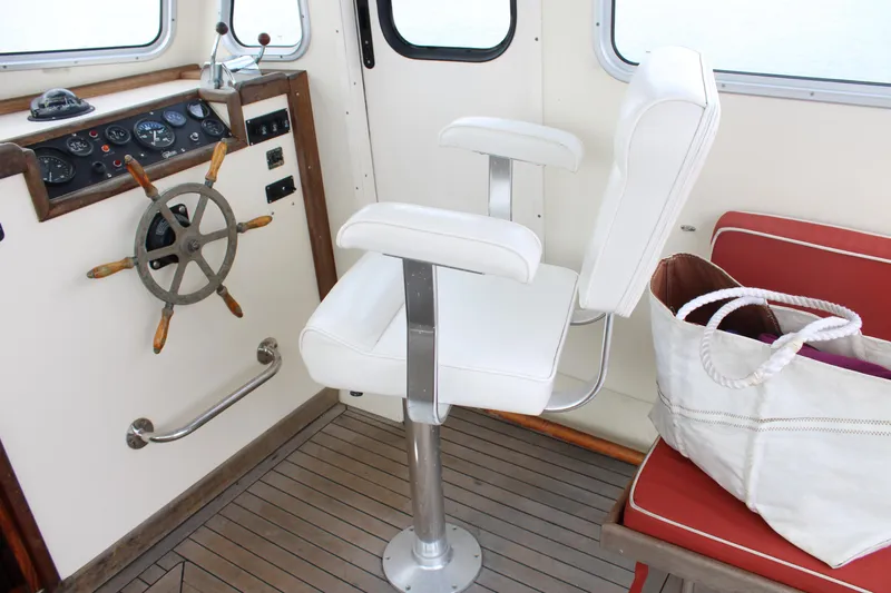 Slide: The Image of Interior of a 1996 Webbers Cove 26 boat with helm, white captain's chair, and red seating. - 10