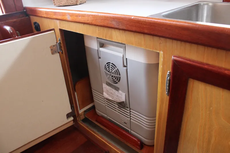 Slide: The Image of Cabinet with a compact refrigerator inside a 1996 Webbers Cove 26 boat kitchen. - 22