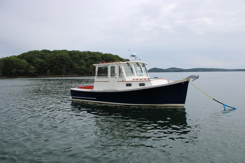 Slide: The Image of 1996 Webbers Cove 26 boat anchored on calm water near a forested shoreline. - 33