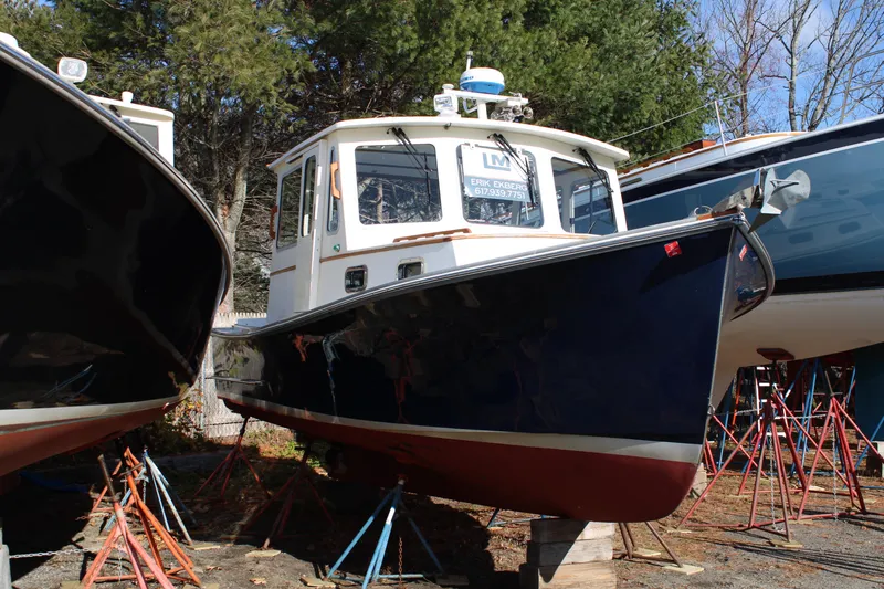 Slide: The Image of 1996 Webbers Cove 26 boat on stands, surrounded by trees and other boats. - 36