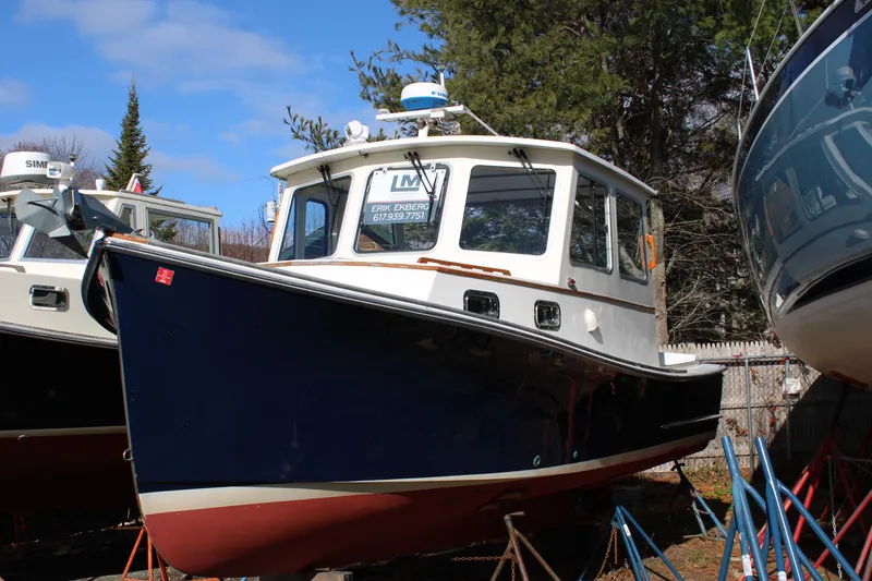 Slide: The Image of 1996 Webbers Cove 26 boat on stands, blue hull, white cabin, outdoor setting. - 37