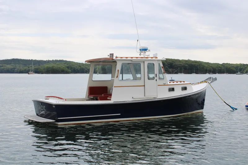 Slide: The Image of 1996 Webbers Cove 26 boat anchored on calm water with scenic background. - 6