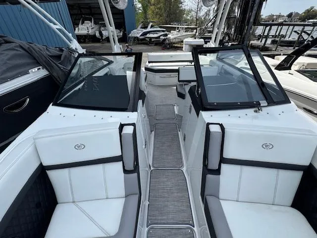 Slide: The Image of 2024 Cobalt R8 boat interior with white seating and dual windshields at a marina. - 16
