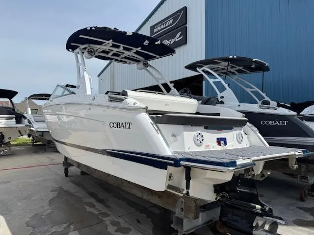 Slide: The Image of 2024 Cobalt R8 boat with sleek design, docked outdoors near a blue building. - 5