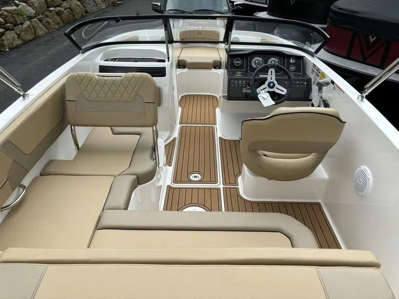 Slide: The Image of 2024 Bayliner VR5 Bowrider interior with tan seating and wood-style flooring. - 6