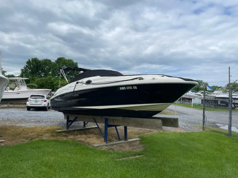 The Image of 2005 Sea Ray 240 Sundeck boat on a stand in a marina. - 0