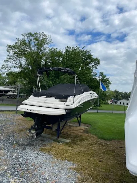Slide: The Image of 2005 Sea Ray 240 Sundeck boat on a stand, covered and parked outdoors. - 2