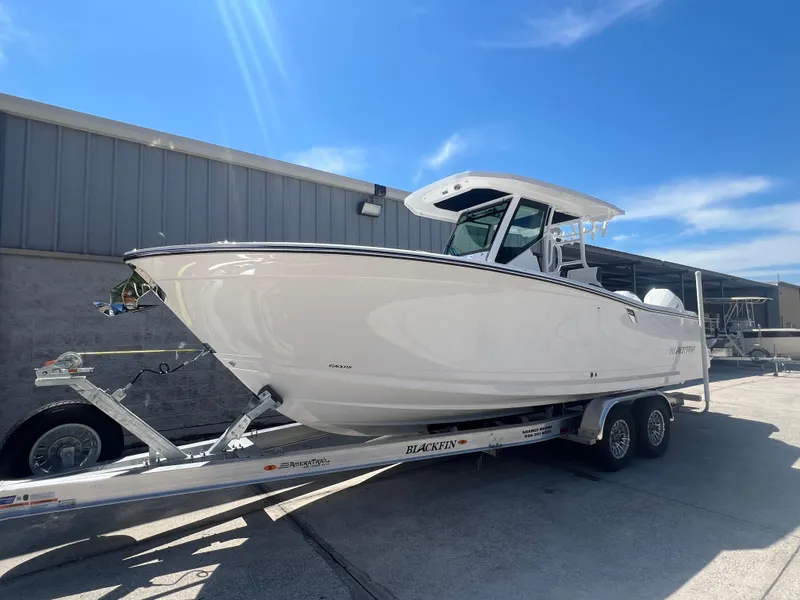 Slide: The Image of 2024 Blackfin 272 CC boat on a trailer under a clear blue sky. - 0