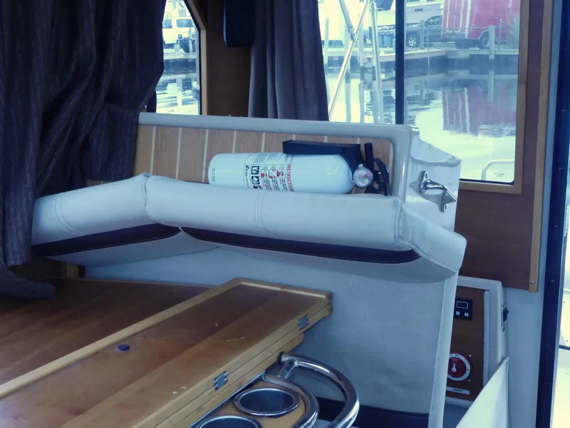 Slide: The Image of Interior of a 2014 Cutwater C 26 boat with a fire extinguisher and wooden table. - 11