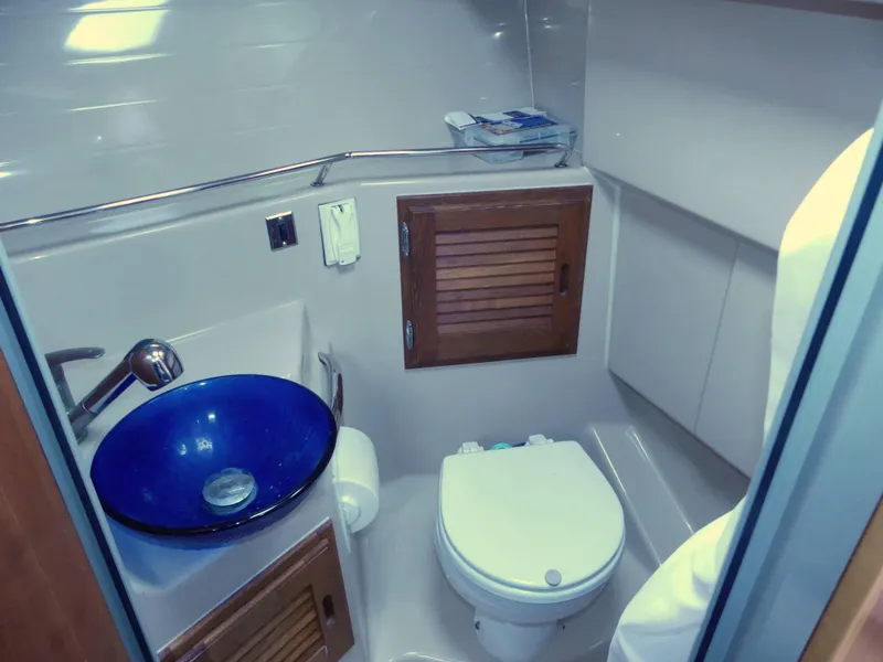 Slide: The Image of Compact bathroom in 2014 Cutwater C 26 boat with blue sink and wooden cabinets. - 10