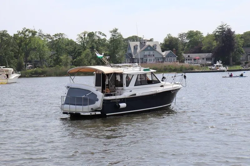 Slide: The Image of 2014 Cutwater C 26 boat cruising on a calm lake with houses in the background. - 2