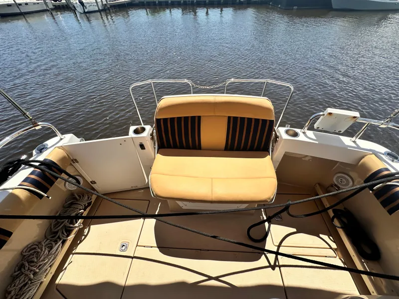 Slide: The Image of 2014 Cutwater C 26 boat with cushioned seating at the stern, docked by the water. - 28