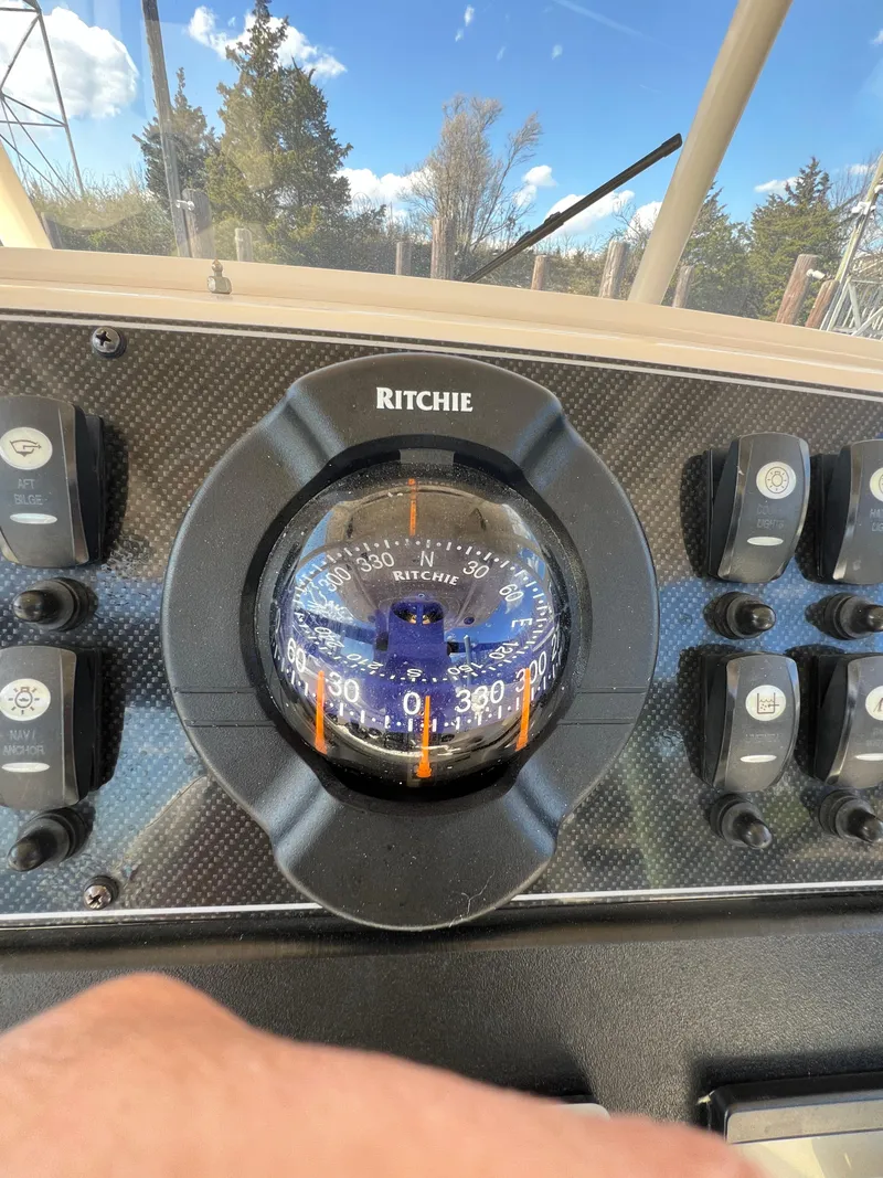 Slide: The Image of Compass on 2019 Grady-White Canyon 306 boat dashboard with control switches. - 20