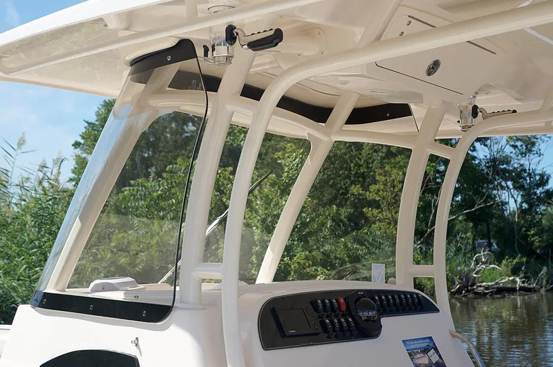 Slide: The Image of 2019 Grady-White Canyon 306 boat console with windshield and controls, surrounded by greenery. - 39