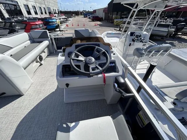 Slide: The Image of 2024 Avalon Venture Quad Lounger 23 FT boat interior with steering wheel and seating. - 11