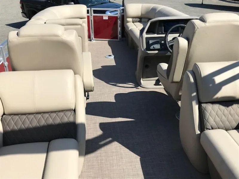 Slide: The Image of 2024 Sun Tracker PB 22 DLX pontoon boat interior with beige seating and steering console. - 2