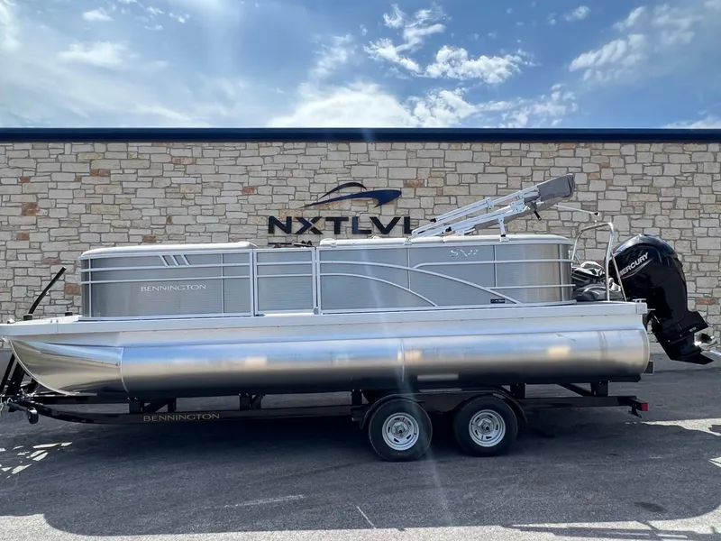 Slide: The Image of 2024 Bennington 22S pontoon boat on trailer, parked outside stone building. - 2