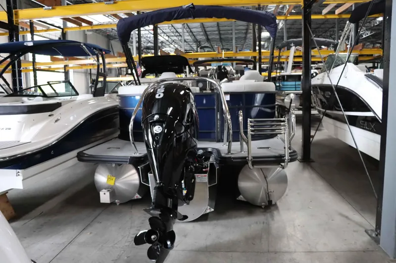 Slide: The Image of 2025 Starcraft EXS 3 pontoon boat in storage, featuring a powerful outboard motor. - 4