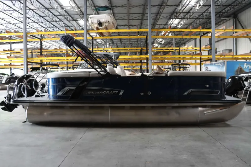 Slide: The Image of 2025 Starcraft EXS 3 pontoon boat in a spacious indoor storage facility. - 3